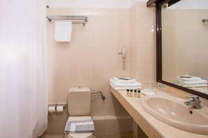 Badezimmer im Hersonissos Palace Hotel mit Dusche, Toilette, Handtüchern und Kosmetikartikeln.