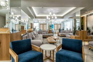 Lobby des Odyssia Beach Hotels mit modernen Möbeln, hellen Farben und großen Spiegeln.