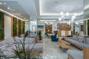 Lobby des Odyssia Beach Hotels mit Sofas, Pflanzen und einer Rezeption.