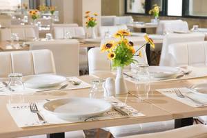 Restauranttisch im Odyssia Beach Hotel, dekoriert mit Sonnenblumen in einer Vase.