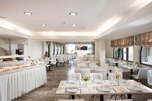 Frühstücksraum des Odyssia Beach Hotels mit weißen Tischen und Stühlen.