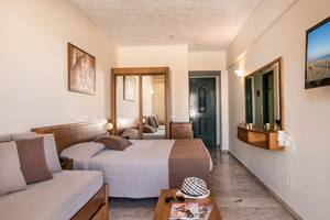 Doppelbett-Hotelzimmer im Odyssia Beach Hotel mit Fernseher, Spiegel und Sofa.