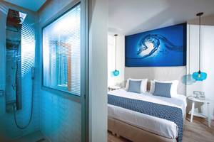 Schlafzimmer und Badezimmer im Odyssia Beach Hotel mit blauem Thema und modernen Möbeln.