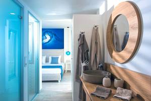 Badezimmer im Odyssia Beach Hotel mit Blick auf das Bett und eine blaue Wand.