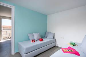 Kinderzimmer im Odyssia Beach Hotel mit zwei Betten, Kissen, und Spielzeug.