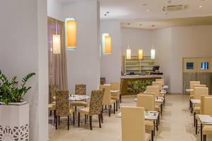 Innenbereich des Stamatia Hotels mit Restaurant, Tischen und Stühlen, Pflanzen und Lampen.
