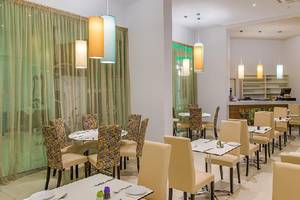 Innenansicht des Restaurants im Stamatia Hotel mit runden Tischen und cremefarbenen Stühlen.