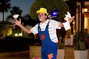 Ein Clown mit einem rosa Hut und einem weißen Tuch in der Hand, der im Stamatia Hotel auftritt.