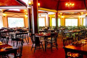 Ein Restaurant des Biyadhoo Island Resorts mit vielen Tischen und Stühlen, Deckenlampen und großen Fenstern.