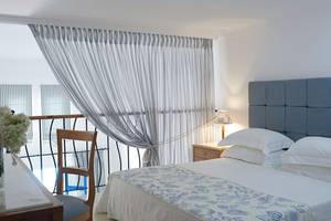 Schlafzimmer im Mitsis Norida Beach Hotel mit Blick auf den Balkon und einem Bett mit weißen Kissen.