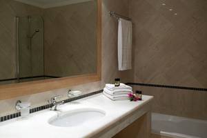 Badezimmer im Mitsis Norida Beach Hotel mit Spiegel, Handtüchern, Flüssigseifen und Badewanne