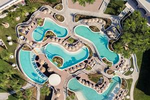 Mitsis Norida Beach Hotel, Pool-Anlage aus der Vogelperspektive, mit mehreren Schwimmbecken und Palmen.