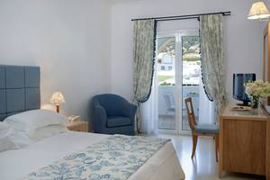 Schlafzimmer im Mitsis Norida Beach Hotel mit Bett, Stuhl, Schreibtisch und Balkon