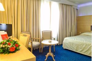Hotelzimmer im El Mouradi Mahdia mit Bett, Schreibtisch, Stühlen und Blumen.