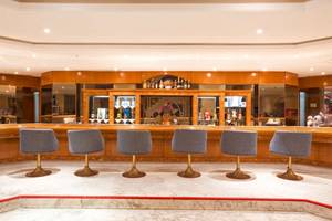 Innenansicht der Bar im El Mouradi Mahdia Hotel mit sechs grauen Stühlen und einer Theke.