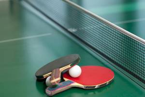 Ping-Pong-Tisch mit Schlägern und Ball auf grüner Oberfläche