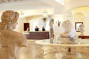 Ein Hotellobby mit Statuen, einer Rezeption und einer Glastisch in der Mitte.