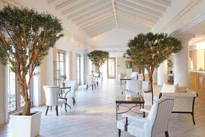 Hotellobby mit Sofas, Tischen und großen Topfpflanzen im Grecotel La Riviera & Aqua Park