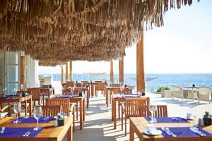 Außenbereich des Restaurants im Grecotel La Riviera & Aqua Park mit Blick auf das Meer.