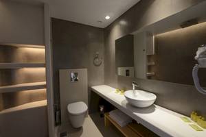 Badezimmer im MykonosView Hotel mit grauen Wänden, weißem Waschbecken und Toilette.