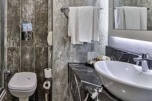 Badezimmer im Saturn Palace Resort mit Dusche, Toilette, Waschbecken und Handtüchern.