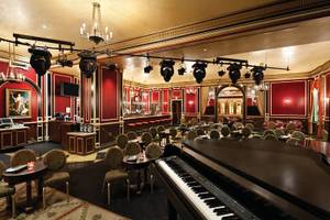 Innenbereich des Paris Las Vegas Hotels mit rotem Dekor, einer großen Klavier, und runden Tischen.