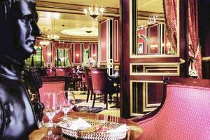 Innenbereich des Paris Las Vegas Hotels mit rotem Dekor, Stühlen, Tisch, Statue und Gläsern.