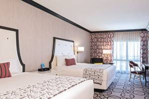 Doppelbett-Zimmer im Paris Las Vegas Hotel mit modernen Dekor, zwei Betten, Nachttischen und Fenstern.