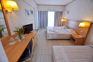 Hotelzimmer des Smy Kos Beach & Splash mit zwei Betten, Fernseher, Schreibtisch und Spiegel.