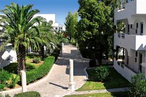 Eingangsbereich des Smy Kos Beach & Splash Hotels mit Palmen und weißen Gebäuden.