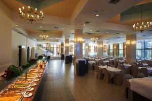 Innenansicht des Restaurants im Smy Kos Beach & Splash Hotel mit vielen Tischen und Stühlen, Buffet und Kronleuchtern.