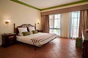 Schlafzimmer im Ali Baba Palast Hotel mit einem Doppelbett, Nachttischen und Fenstern.