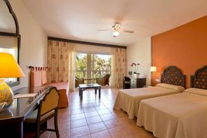 Doppelzimmer im Bluebay Banus Hotel mit zwei Betten, Schreibtisch, Lampe und Balkon.
