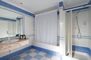 Badezimmer im Bluebay Banus Hotel mit blauen Fliesen und Marmorarbeitsplatte.