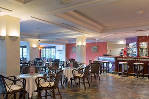 Innenansicht des Bluebay Banus Hotel Restaurants mit Tischen, Stühlen und einer Bar.