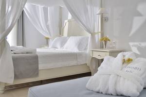 Schlafzimmer im Kamari Hotel mit einem Bett, das unter einem Baldachin versteckt ist.