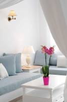 Wohnzimmer des Kamari Hotels mit weißem Sofa, Kissen, Tisch, Lampe und Orchidee