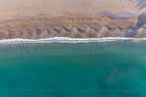 Oberflächenansicht eines Strandes mit türkisfarbenem Meer und Sonnenschirm