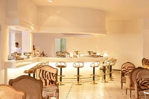 Barbereich des Grecotel Caramel Boutique Resorts mit modernen Stühlen und einer großen Theke.