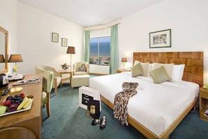 Innenansicht eines Zimmers im BM Beach Hotel mit Bett, Schreibtisch, Fernseher und Fenster mit Meerblick.
