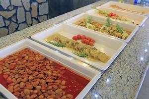 Mehrere Gerichte auf Platten serviert, einschließlich gegrilltes Fleisch, Bohnen und Tomaten.