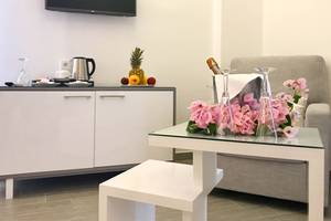 Wohnbereich im Bruskos Hotel mit Fernseher, Tisch mit Blumen und Früchten, und Sofa.