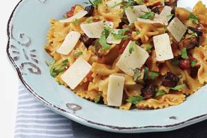 Nahaufnahme von Pasta mit Pilzen und Tomaten auf einem blauen Teller