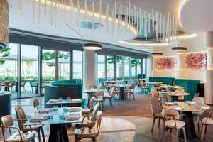 Innenansicht des Restaurants im W Dubai - The Palm mit modernen Möbeln und Glaswänden.