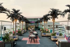 Dachterrasse des W Dubai - The Palm mit bunten Sitzbereichen und Palmen