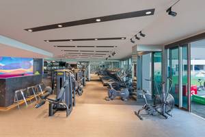 Innenansicht des Fitnessstudios im W Dubai - The Palm mit verschiedenen Trainingsgeräten und einer offenen Glastür.