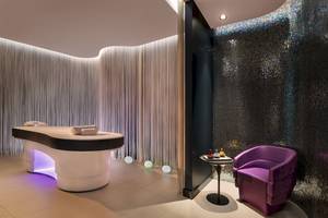 Behandlungsraum im W Dubai - The Palm Hotel mit Massageliege und violettem Stuhl.