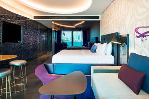 Innenansicht der Suite im W Dubai - The Palm mit Bett, Sofa, Tisch und Aussicht auf die Stadt.