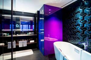 Badezimmer im W Dubai - The Palm Hotel mit violetter Wand und Badewanne.