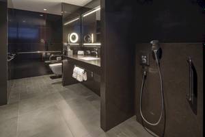 Badezimmer im W Dubai - The Palm Hotel mit schwarzen Wänden, gefliestem Boden und moderner Duschvorrichtung.